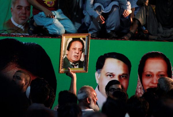 A supporter of former Pakistani prime minister Nawaz Sharif holds his picture as he waits for his convoy to pass through in Rawalpindi, Pakistan, 10 August 2017. (Photo: Reuters/Faisal Mahmoud).