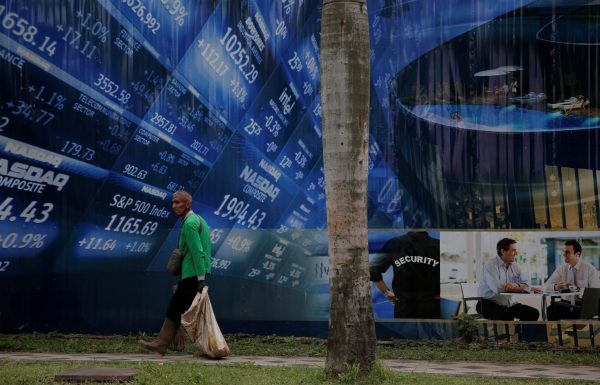A worker walks in front of a stock market poster at Sudirman Business District compound in Jakarta, Indonesia, 9 January 2017 (Photo: Reuters/Beawiharta).