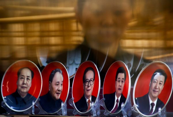 A woman is reflected in a shop window as she looks at souvenir plates with portraits of former Chinese leaders Mao Zedong, Deng Xiaoping, Jiang Zemin, Hu Jintao and current President Xi Jinping in Beijing, China, 25 October 2016 (Photo: Reuters/Thomas Peter).