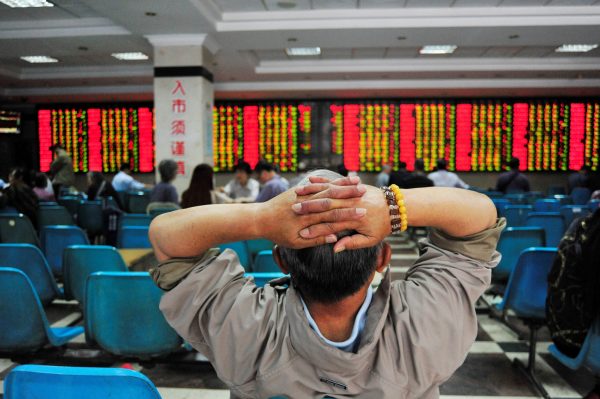 An investor looks at an electronic board showing stock information at a brokerage house in Nanjing, China, 24 May 2017. (Photo: Reuters/Stringer).