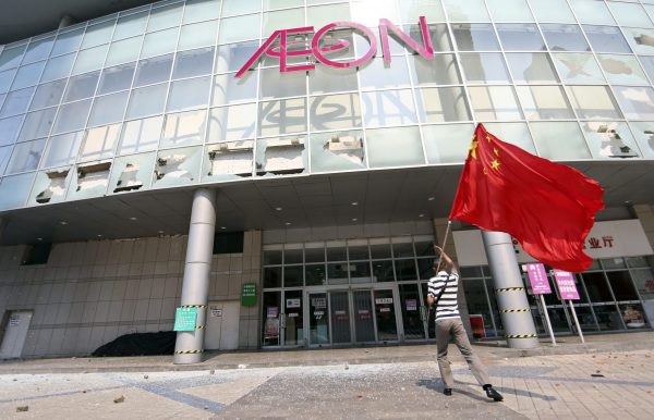 A flag-waving demonstrator outside the shattered facade of a Japanese-backed shopping centre in Qingdao. Japanese firms hope that social responsibility programs can improve Chinese perceptions. (Photo: Reuters).
