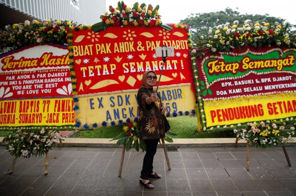 A woman takes her picture with some of the many flower boards, sent by supporters of outgoing Jakarta governor Basuki ‘Ahok’ Tjahaja Purnama just after he lost Jakarta’s gubernatorial election in Jakarta, Indonesia, 27 April 2017 (Photo: Reuters/Darren Whiteside).