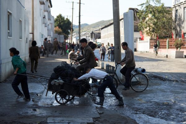 People pull and push a cart through the streets of central Wonsan, North Korea, October 2016 (Photo: Christian Petersen-Clausen/Handout via Reuters).