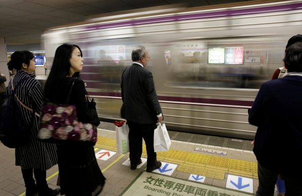 Commuters and an office worker wait for a train in Osaka, western Japan, 24 October 2017. (Photo: Reuters/Thomas White).