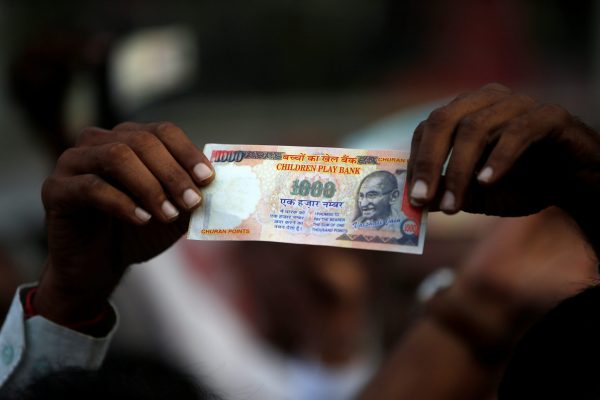 A demonstrator shows an old fake 1000 rupee note during a protest, organised by India's main opposition Congress party, to mark a year since demonetisation was implemented by Prime Minister Narendra Modi, in Ahmedabad, India, 8 November 2017. (Photo: Reuters/Amit Dave).
