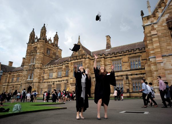 School of Business graduates toss their hats into the air for family members to take pictures outside the main building at the University of Sydney in Australia, 22 April 2016. (Photo: Reuters/Jason Reed).