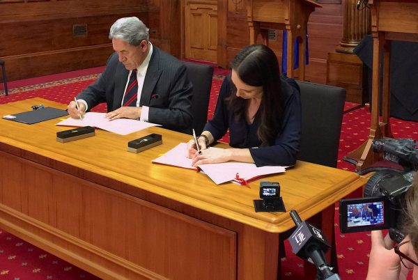 New Zealand Prime Minister Jacinda Ardern signs official documents next to New Zealand First party leader Winston Peters after their meeting in Wellington, New Zealand, 24 October 2017 (Photo: Reuters/Nicolaci da Costa).