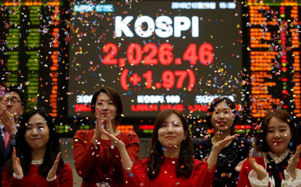 Employees of the Korea Exchange pose in front of the final stock price index during a photo opportunity for the media at the ceremonial closing event of the 2016 stock market in Seoul, South Korea, 29 December 2016 (Photo: Reuters/Kim Hong-Ji).