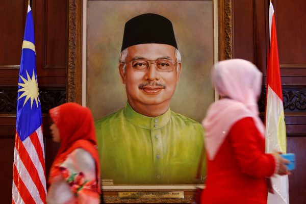 Women walk past a portrait of Malaysia's Prime Minister Najib Razak during the United Malays National Organization (UMNO) general assembly in Kuala Lumpur, Malaysia 7 December, 2017 (Photo: Reuters/Lai Seng Sin).
