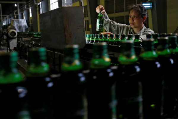 A worker checks for faults on beer bottles which move along a production line in a factory of Saigon Beer Corporation (Sabeco) in Hanoi, Vietnam, 23 June 2017 (Photo: Reuters/Nguyen Huy Kham).