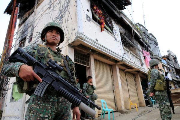 Government soldiers stand guard in front of damaged building and houses in Sultan Omar Dianalan boulevard at Mapandi district in Marawi city, southern Philippines, 13 September 2017 (Picture: Reuters/Romeo Ranoco).