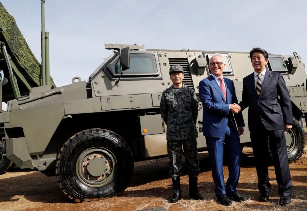 Australian Prime Minister Malcolm Turnbull shakes hands with Japanese Prime Minister Shinzo Abe in front of a Bushmaster military vehicle at Camp Narashino, Japan, 18 January 2018 (Photo: Reuters/Kim Kyung-Hoon).