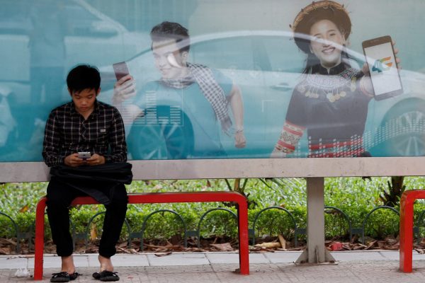 An internet user browses internet in front of an advertising billboard for 4G connection service at a bus stop in Hanoi, Vietnam, 29 August 2017 (Photo: Reuters/Kham).