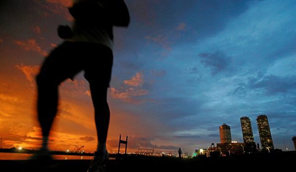 Financial district of Colombo is seen as a man runs along a path in front of the Colombo Port City construction site in Colombo, Sri Lanka 22 November 2017 (Photo: Reuters/Dinuka Liyanawatte).