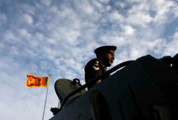 An Army soldier looks on from a tank, as Sri Lanka's national flag is seen in the background, at the parade during a rehearsal for Sri Lanka's 70th Independence day celebrations in Colombo, Sri Lanka, 1 February 2018 (Photo: Reuters/Dinuka Liyanawatte).