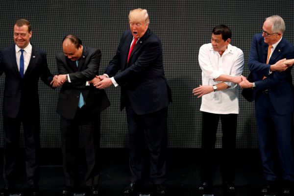US President Donald Trump registers his surprise as he realises other leaders, including Russia's Prime Minister Dmitry Medvedev, Vietnam's Prime Minister Nguyen Xuan Phuc, President of the Philippines Rodrigo Duterte and Australia's Prime Minister Malcolm Turnbull, are crossing their arms for the traditional 'ASEAN handshake' at the opening ceremony of the ASEAN Summit in Manila on 13 November 2017. (Photo: Reuters/Jonathan Ernst).
