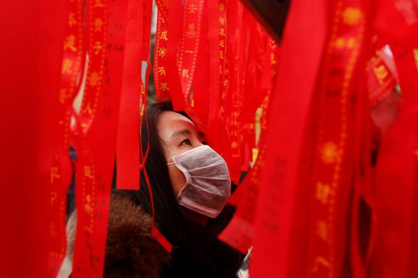 A woman reads ribbons at a wishing tree in Badachu park during Spring Festival celebrations marking Chinese New Year in Beijing, China, 17 February 2018 (Photo: Reuters/Thomas Peter).