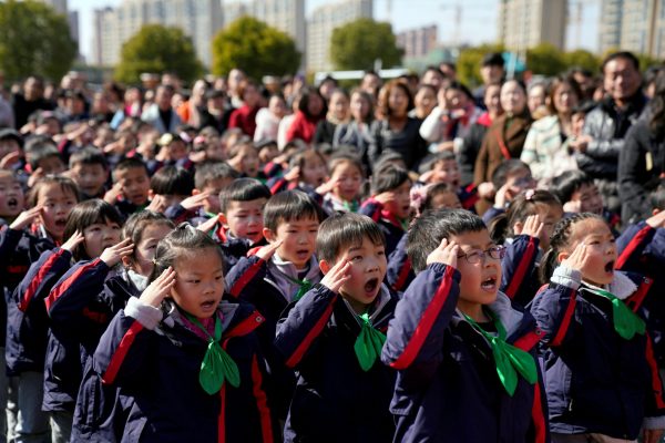Pupils salute during a flag raising ceremony on their first day of the new semester at a primary school in Shanghai, China, 23 February 2018 (Photo: Reuters/Aly Song).