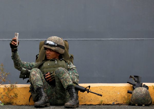 A Philippine marine soldier takes a selfie with his phone during their arrival from Marawi at port area in metro Manila, Philippines, 30 October 2017 (Photo: Reuters/Dondi Tawatao).