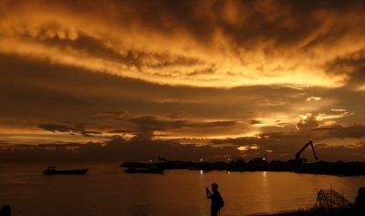 A man takes pictures as the sun sets in front of the Chinese invested Colombo Port City project in Colombo, Sri Lanka, 22 November 2017 (Photo: Reuters/Dinuka Liyanawatte).