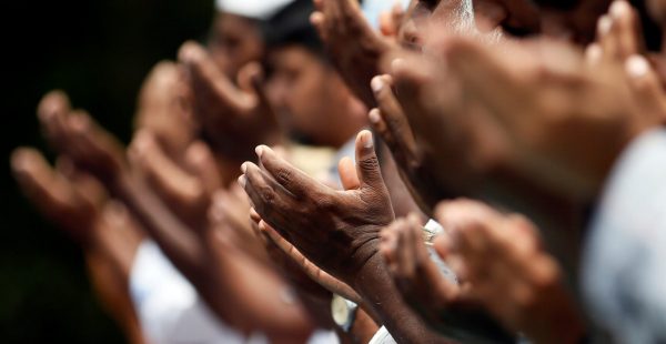 Muslim men pray at a ground after a mosque burned down following a clash between two communities in Digana central district of Kandy, Sri Lanka, 9 March 2018 (Photo: Reuters/Dinuka Liyanawatte).
