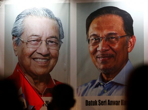 People pass posters of Malaysian Prime Minister Mahathir Mohamad and prime minister-in-waiting Anwar Ibrahim at a rally in Kuala Lumpur, Malaysia, 16 May 2018 (Photo: Reuters/Lai Seng Sin).