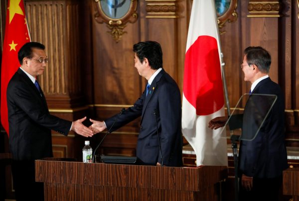 Japanese Prime Minister Shinzo Abe shakes hands with Chinese Premier Li Keqiang as South Korean President Moon Jae-in looks on, at the end of their joint news conference following the seventh Japan-China-South Korea trilateral summit talks in Tokyo, 9 May 2018 (Photo: Reuters/Kimimasa Mayama).
