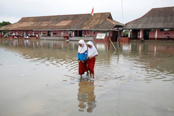 Students walk in the yard of the Pantai Bahagia Elementary School, inundated with sea water after the tide came in, in Bekasi, West Java province, Indonesia, 1 February 2018 (Photo: Reuters/Darren Whiteside).