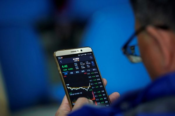 An investor checks stock information on a mobile phone at a brokerage house in Shanghai, China, 9 February 2018 (Photo: Reuters/Aly Song).