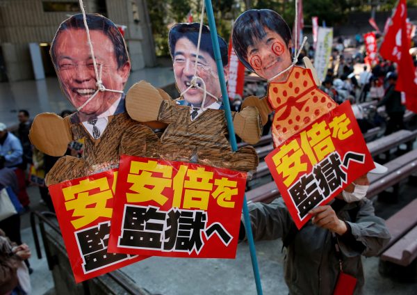 Protesters hold placards during a rally denouncing Japanese Prime Minister Shinzo Abe, his wife Akie, and Finance Minister Taro Aso over a suspected cover-up of a cronyism scandal in Tokyo, Japan, 25 March 2018 (Photo: Reuters/Issei Kato).