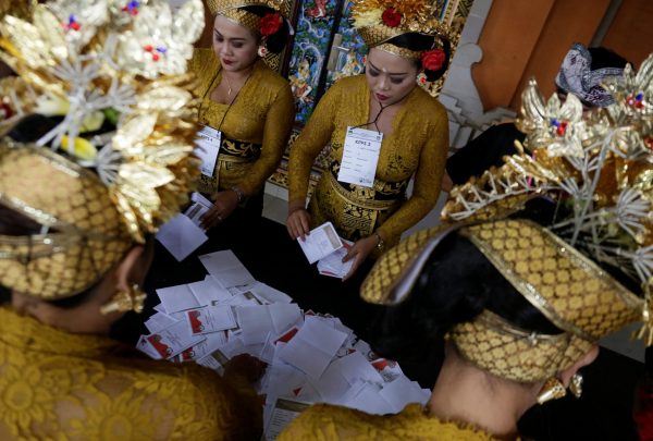 Election officials wearing traditional Balinese costume prepare ballots for counting after polls closed at a polling station during local elections in Badung Regency, Bali, Indonesia, 27 June 2018 (Photo: Reuters/Johannes P. Christo).