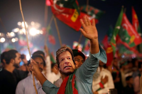 A supporter of Imran Khan, chairman of the Pakistan Tehreek-e-Insaf (PTI) party, wears a mask and dance on party songs during a campaign rally ahead of general elections, Karachi, 22 July 2018 (Photo: Reuters/Akhtar Soomro).