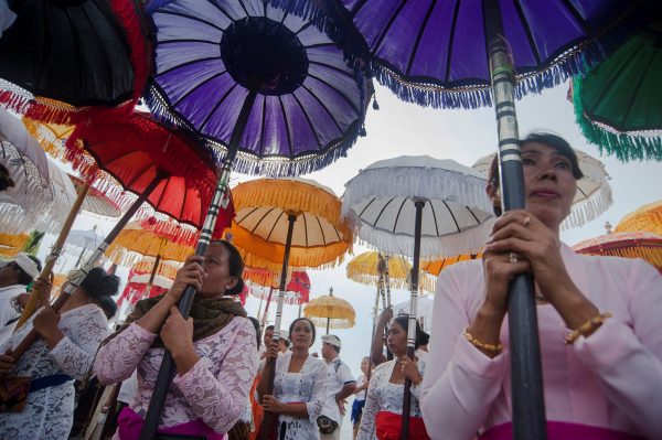 Balinese women hold umbrellas as they stand during a Melasti ceremony ahead of Nyepi Day at the Padanggalak beach in Denpasar, Indonesia, 24 March 2017 (Photo: Reuters/Antara Foto/Nyoman Budhiana).