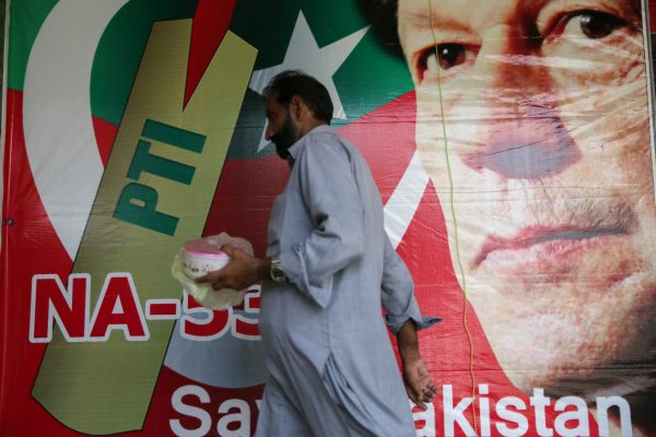 A man walks past an image of cricket star-turned-politician Imran Khan, chairman of Pakistan Tehreek-e-Insaf (PTI) at a market in Islamabad, Pakistan, 27 July 2018 (Photo: Reuters/Athit Perawongmetha).