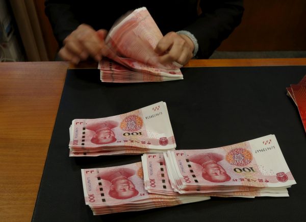 A staffer poses with 2015 edition of the 100 renminbi notes at the Bank of China Tower in Hong Kong, China, 12 November 2015 (Photo: Reuters/Bobby Yip).
