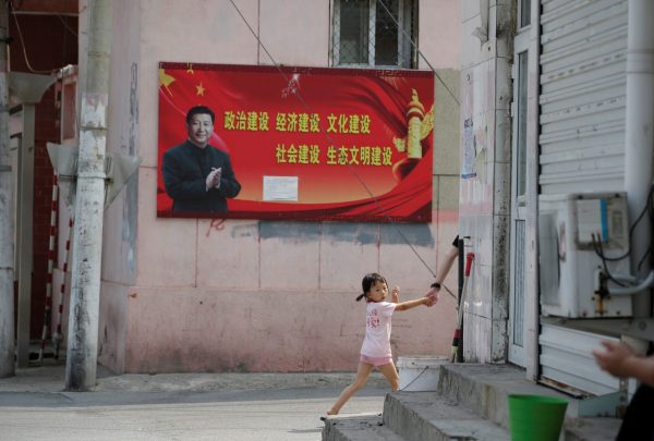 A girl walks past a poster with a portrait of Chinese President Xi Jinping at a village on the outskirts of Beijing, China, 3 August 2018 (Photo: Reuters/Jason Lee).