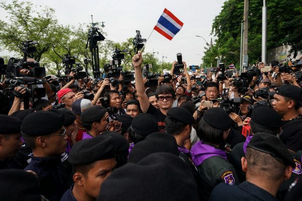 Pro-democracy activist Rome Rangsiman (C) holds up a Thailand flag as anti-government protesters gather during a protest to demand that the military government hold a general election by November, in Bangkok, Thailand, 22 May 2018 (Photo: Reuters/Athit Perawongmetha).
