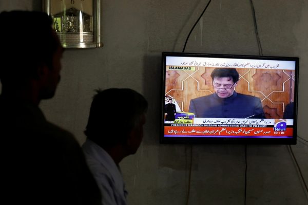 Men look at a television screen displaying cricketer-turned-politician Imran Khan swearing in as Prime Minister of Pakistan, in Karachi, Pakistan, 18 August 2018 (Photo: Reuters/Akhtar Soomro).