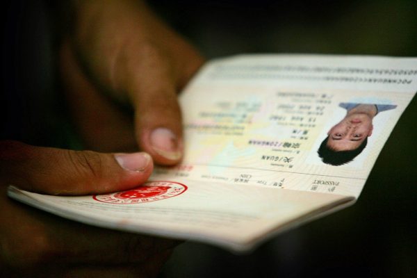 A Solomon Islander of Chinese descent holds his passport as officials organise flights to China for people targeted by rioters in Honiara, Solomon Islands, 23 April 2006 (Photo: Reuters/Tim Wimborne).