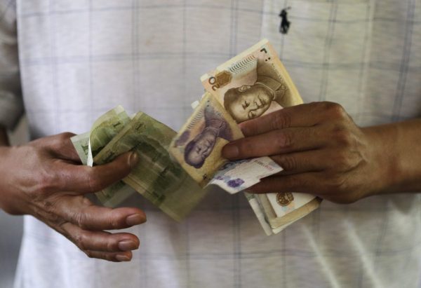 A customer counts Chinese Yuan notes at a market in Beijing, 12 August 2015. China shocked global markets on Tuesday by devaluing its currency after a run of poor economic data, a move it billed as a free-market reform but which some experts suspect could be the beginning of a longer-term slide in the exchange rate (Photo: Reuters/Jason Lee).