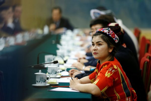 A delegate wearing a traditional costume attends a session of the Xinjiang Uyghur Autonomous Region on the sidelines of the National People's Congress (NPC) at the Great Hall of the People in Beijing, China, 13 March 2018 (Photo: Reuters/Thomas Peter).