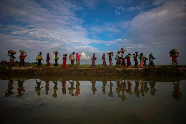 Rohingya refugees are reflected in rain water along an embankment next to paddy fields after fleeing from Myanmar into Palang Khali, near Cox's Bazar, Bangladesh, 2 November 2017 (Photo: Reuters/Hannah McKay).
