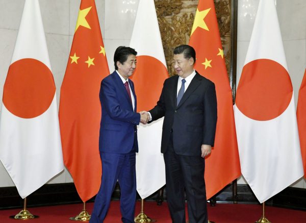 Japanese Prime Minister Shinzo Abe (left) shakes hands with Chinese President Xi Jinping during a meeting in Beijing, China, 26 October 2018 (Photo: Kyodo via Reuters).