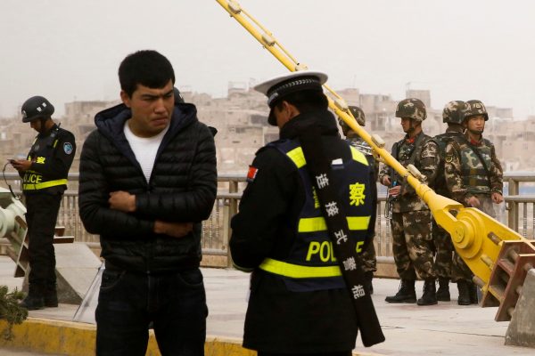 A police officer checks the identity card of a man as security forces keep watch in a street in Kashgar, Xinjiang Uighur Autonomous Region, China, 24 March 2017 (Photo: Reuters/Thomas Peter/File Photo).