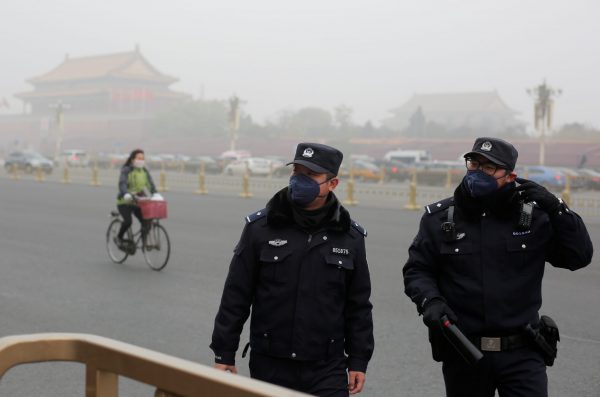 Police officers wear masks as Tiananmen Square is shrouded in haze after an alert was issued for smog in Beijing, China, 14 November 2018 (Photo: Reuters/Thomas Peter).