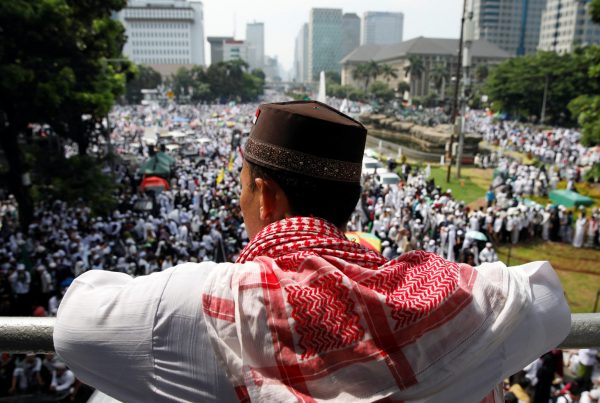 A man watches a rally attended by tens of thousands of Indonesian Muslims to commemorate a series of rallies held in late 2016 targeting the city's former Christian governor Basuki Tjahaja Purnama, in Jakarta, Indonesia, 2 December 2018 (Photo: Reuters/Darren Whiteside).