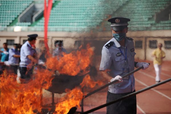 A policeman burns seized drugs at an oath-taking rally before the International Day Against Drug Abuse and Illicit Trafficking in Fuyang, Anhui province, China, 23 June 2018 (Photo: Reuters/Stringer).