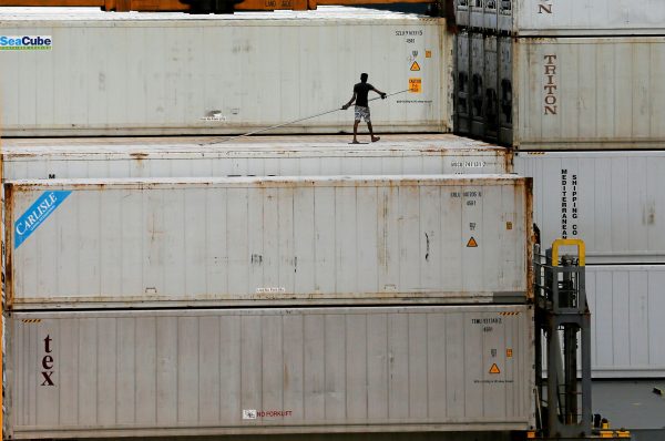 A dock worker is seen on top of shipping containers in a ship at the main port in Colombo, Sri Lanka, 21 June 2018 (Photo: Reuters/Dinuka Liyanawatte).