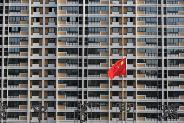 A Chinese flag flutters in front of a residential building under construction in Huai’an, Jiangsu Province, China, 12 July 2018 (Photo: Reuters/Stringer).