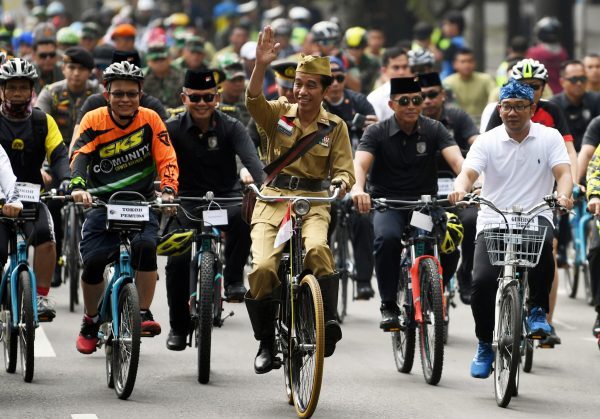 Indonesia's President Joko Widodo wearing a uniform worn by an Indonesian military leader during the revolution against Dutch rules, waves to people as he rides a bicycle with West Java governor Ridwan Kamil in commemoration of Heroes' Day on a street in Bandung, Indonesia, 10 November 2018 (Photo: Reuters/Wahyu Putro).